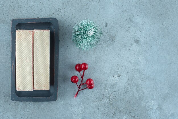 Strawberry cream filled wafers in a small tray next to christmas ornaments on marble surface