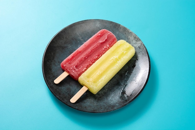 Free photo strawberry and lemon popsicles on blue background