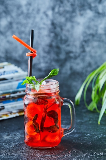 Strawberry lemonade with ice, straw mint in the dark surface 