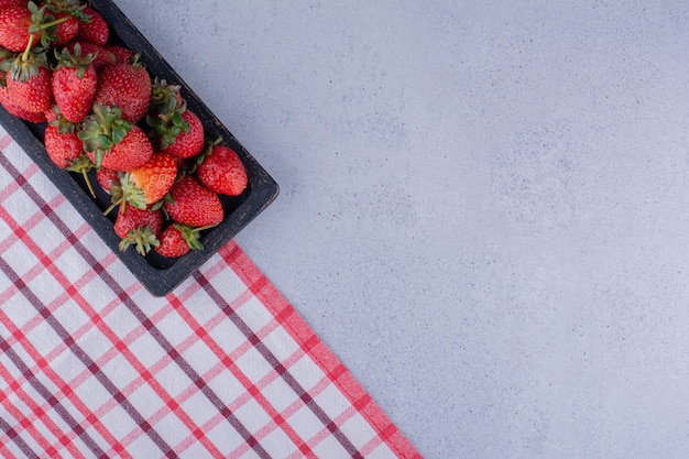 Strawberry tray lined up at the edge of the tablecloth on marble background. High quality photo