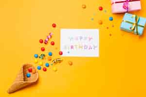 Free photo streamers and gems on waffle with happy birthday on paper against yellow background