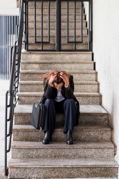 Stressed business woman sitting on stairs 