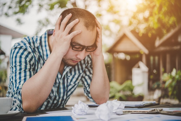 Stressed businessman with papers and charts sitting at table at home. Businessman with paperwork and deadline concept.