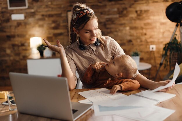 Stressed mother talking to her son while trying to work at home