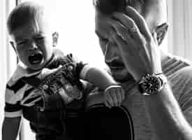 Free photo stressed out father holding a crying baby