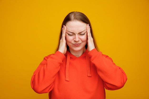 Free photo stressed young blonde woman keeping hands on head with closed eyes