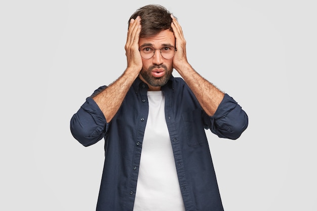 Stressful displeased student posing against the white wall