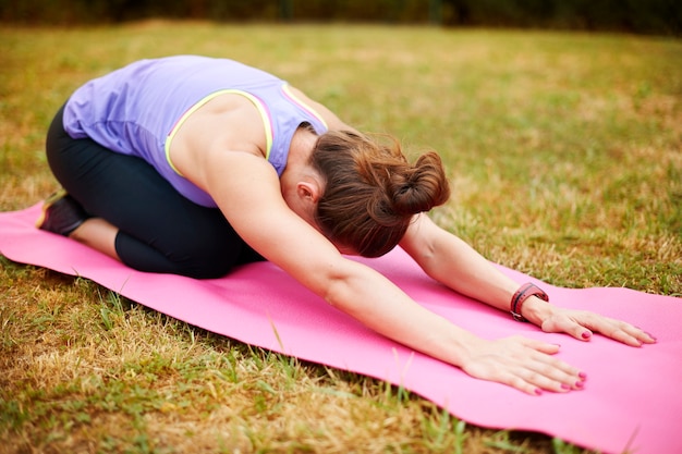 Free photo stretching is very important after physical exercises. young woman doing yoga outside.