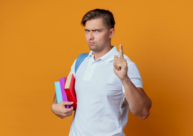 Strict young handsome male student wearing back bag holding books