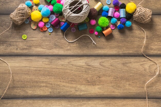 String spool; colorful buttons; spool and cotton balls on wooden plank