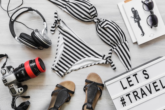 Free Photo striped female bikini swimsuit with travelling accessories on desk