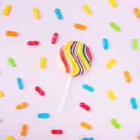 Free photo striped lollipop with colorful candies over the pink backdrop