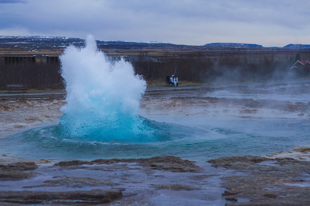 Free Photo strokkur geyser surrounded by hills under a cloudy sky in the evening in iceland