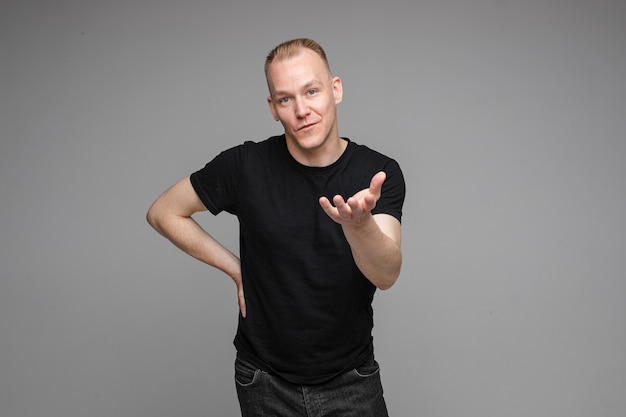 Free Photo strong caucasian man with short fair hair wearing a black t-shirt and jeans tries to explain something