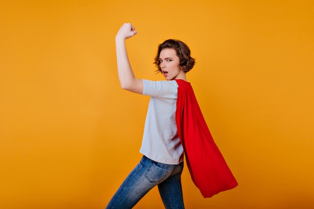 Free photo strong girl in denim pants and blue t-shirt posing with hand up