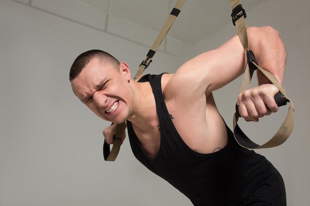 Free photo strong man in black sporty uniform having hard training at gym. sport concept.