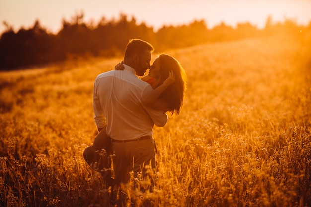 Strong man holds charming lady on his arms and walks