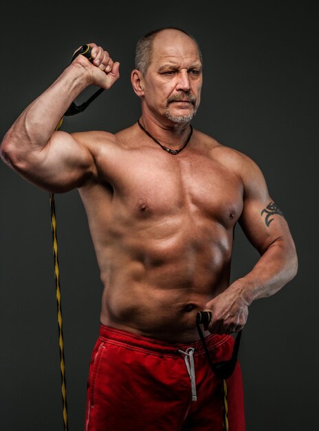 Strong muscular middle age man posing in studio. Isolated on grey.