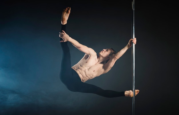 Free Photo strong young man performing a pole dance