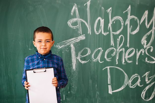 Free photo student boy standing on blackboard background on teachers day