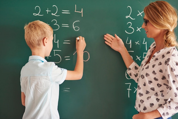 Student boy with chalk next to the chalkboard