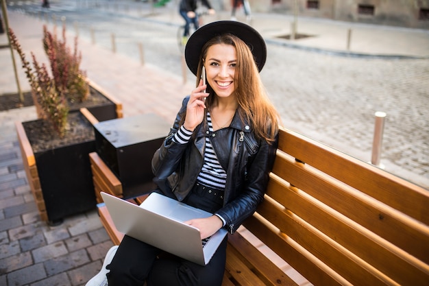 Student girl business woman sit on wood bench in the city in the park in autumn day