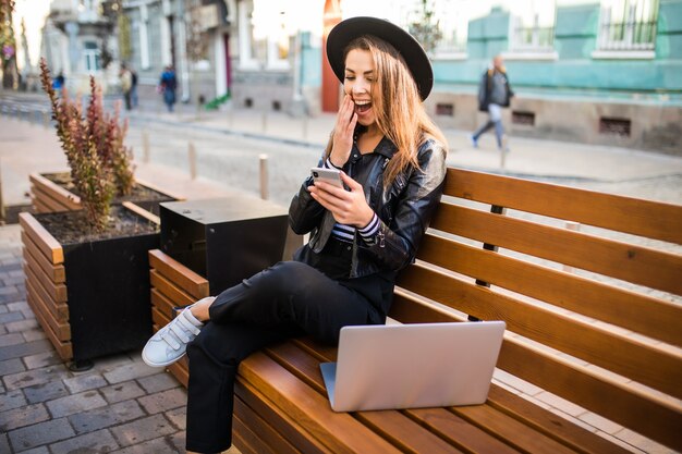 Student girl business woman sit on wood bench in the city in the park in autumn