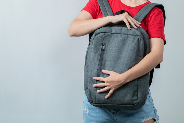 Student holding the grey backpack in the front