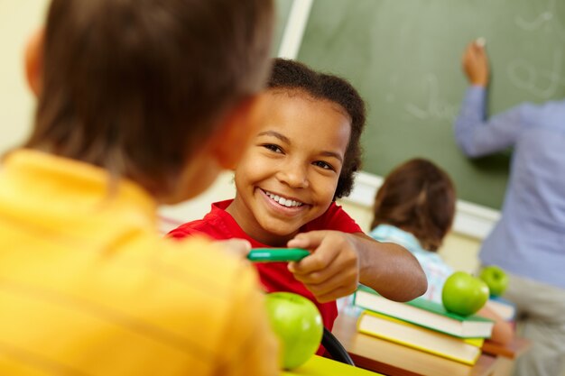 Student holding her green pencil with teacher background