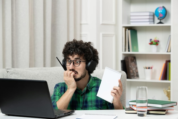 Free photo student online cute young guy studying on computer in glasses in green shirt biting finger