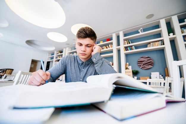 Student reading with books on table in library