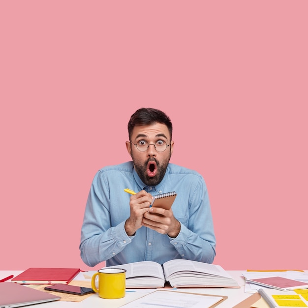 Free photo student sitting at desk with documents holding notebook