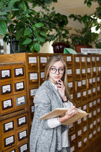 Student with book thinking near catalog