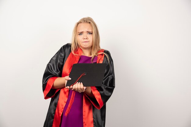 student woman holding her cap on white.