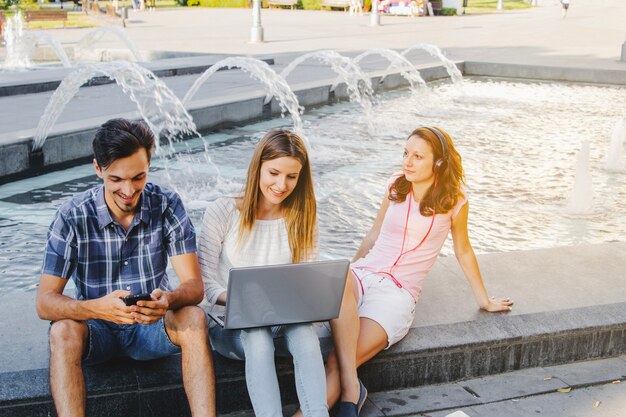 Free photo students relaxing on fountain