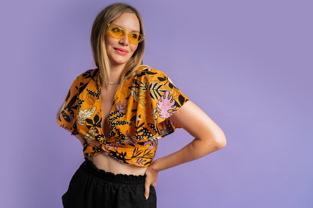 Studio   close up fashion  portrait  of pretty blond woman in stylish top and  linen shorts posing on purple background