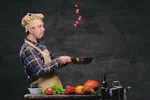 Free photo studio image of male chef cook preparing meals on a pan.