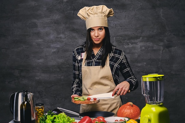 Free photo studio portrait of chef female cook at the table with a lot of vegetables.