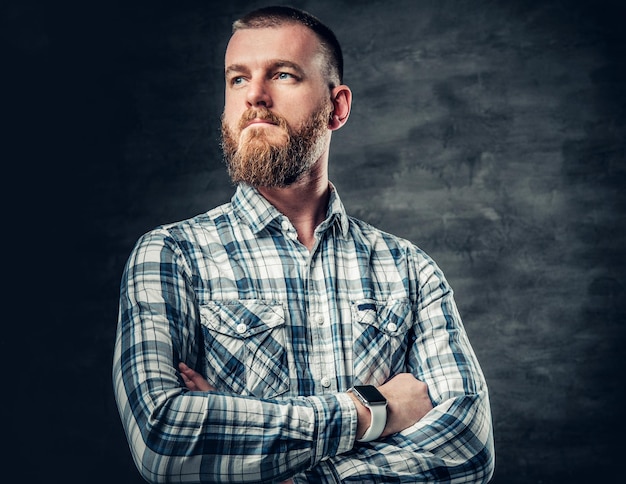 Studio portrait of redhead bearded male dressed in afleece shirt over grey background.