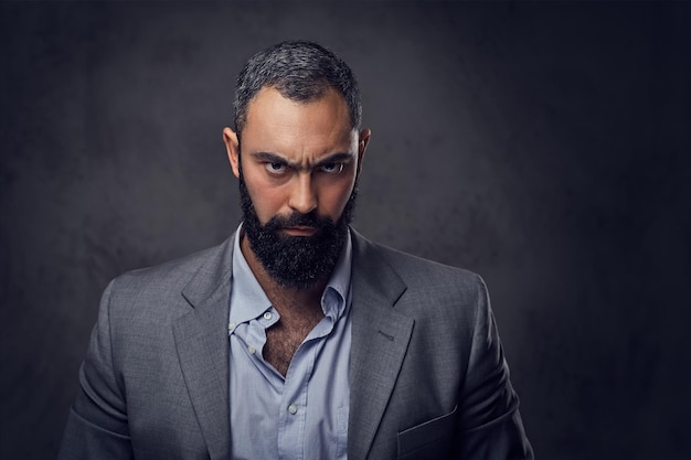 Studio portrait of serious, bearded male dressed in a suit.