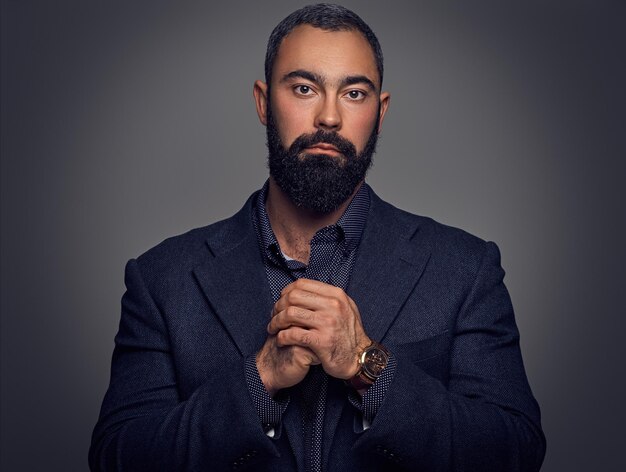 Studio portrait of serious, bearded male dressed in a suit.