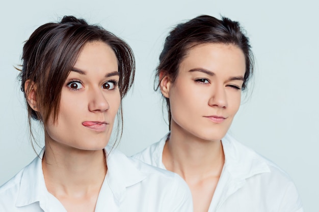 Studio portrait of young female twins sisters on gray