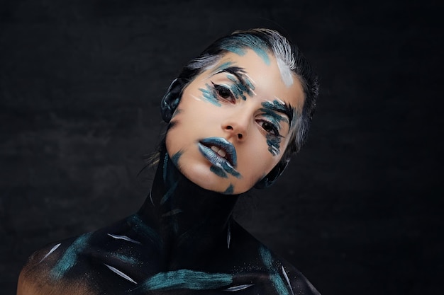 Studio portrait of young female with colorful make up and painted art on a neck.