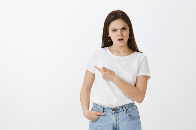 Studio shot of doubtful young woman posing against white wall