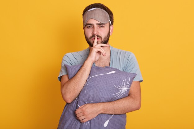 Studio shot of handsome with beard man standing against yellow studio wall