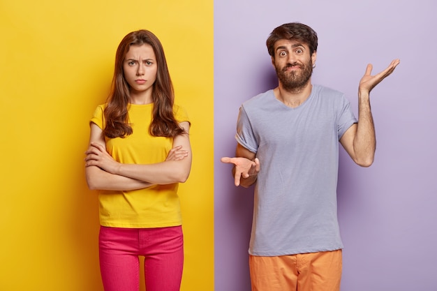 Free Photo studio shot of puzzled millennial couple posing against the dual colored wall