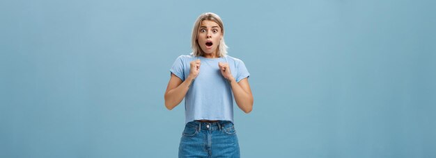 Studio shot of stunned shocked girl standing in stupor with dropped jaw and frightened look