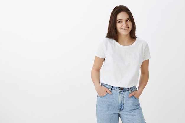 Studio shot of stylish young woman posing against white wall