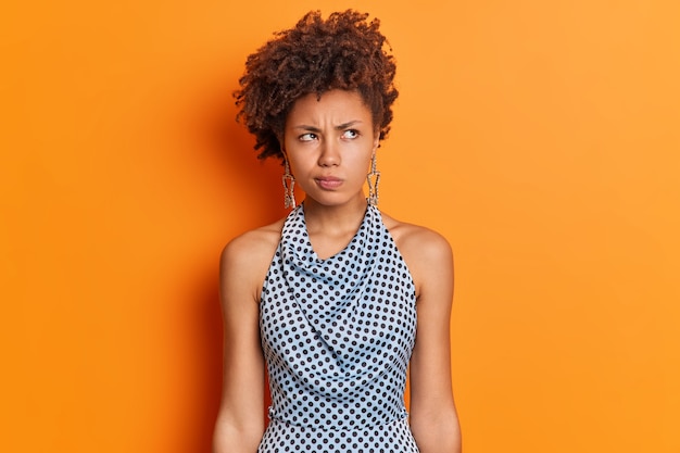 Free photo studio shot of thoughtful displeased ethnic woman smirks face doesnt like idea concentrated aside