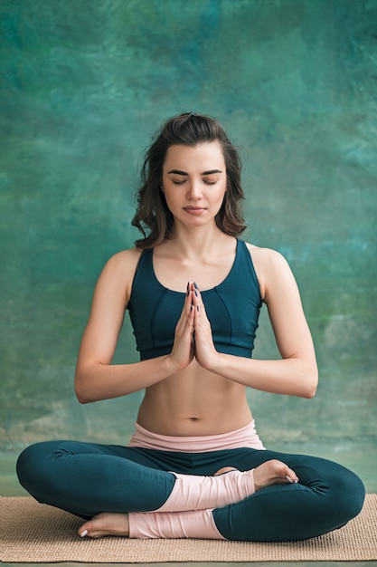 Studio shot of a young fit woman doing yoga exercises on green space